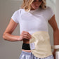 A woman wearing a white t-shirt and striped pajama pants demonstrates a beige maternity support belt with a black undergarment, showing how the support belt fits around her midsection. doTERRA Castor Oil Canada