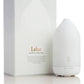 A white essential oil diffuser bottle standing next to its white packaging box, which features the brand name 'Laluz' in gold text. dōTERRA Laluz Diffuser with Peppermint & Wild Orange