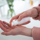 Person applying a white bottle of lotion to their hand with a blurred background