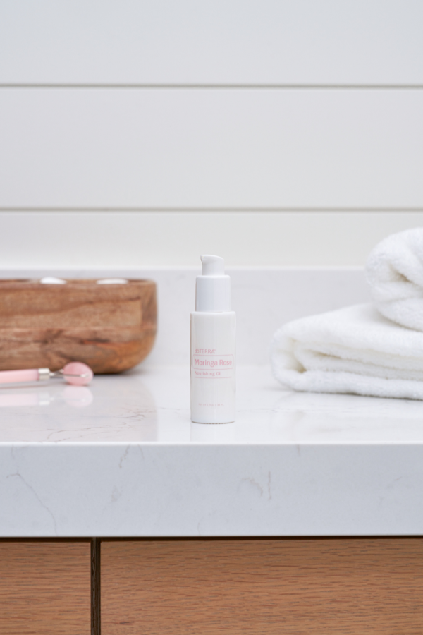 Cosmetic bottle on a bathroom counter with a towel and wooden cutting board in the background