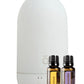 A white diffuser bottle with two small essential oil bottles labeled Lemon and Lavender, shown on a clean white background. dōTERRA Laluz Diffuser with Lemon and Lavender